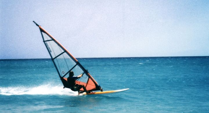 Windsurfen unterscheidet sich vom herkömmlichen Surfen darin, dass an dem Surfbrett ein Segel befestigt ist, welches die Fortbewegung durch Drehen und Kippen steuert.